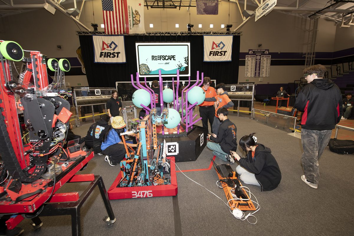 Student teams prepare their robots at a FIRST Robotics competition.